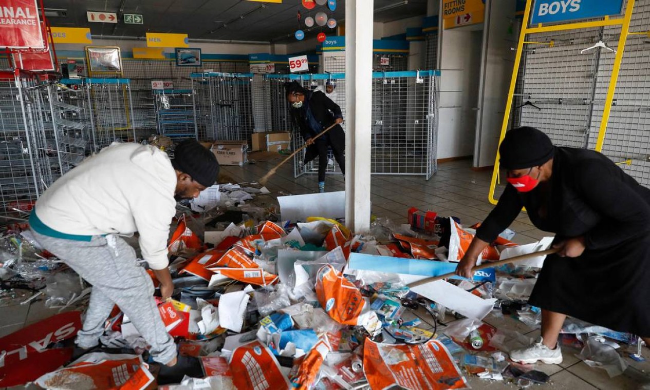 Voluntários trabalham para limpar o interior de uma loja de roupas na Diepkloof Square após saques e vandalismo em Soweto, Joanesburg, devido a protestos contra a prisão de ex-presidente Jacob Zuma. Foram contabilizados, até agora, 72 mortos em confronto Foto: PHILL MAGAKOE / AFP