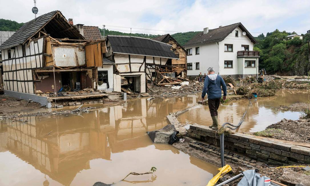 Ein Mann geht in Schuld bei Bad Neuenahr durch eine überflutete Straße und durch Starkregen zerstörte Häuser Foto: BERND LAUTER / AFP