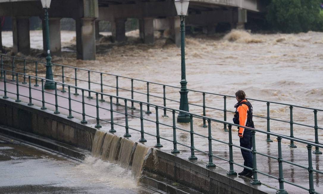 Un poliziotto che osserva l'acqua del fiume Mosa rompe una barricata all'incrocio con Orth, a Liegi. Foto: Anthony Dehes/AFP