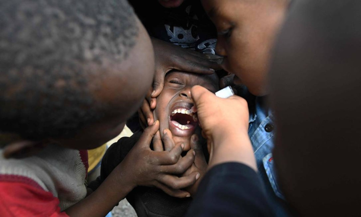 Agente comunitário de saúde entrega uma vacina contra a poliomielite, em Kiamako, Nairóbi. Três milhões de crianças em 13 condados do Quênia serão vacinados contra a poliomielite pelo governo, UNICEF, OMS e parceiros, após a confirmação da circulação do vírus Foto: SIMON MAINA / AFP