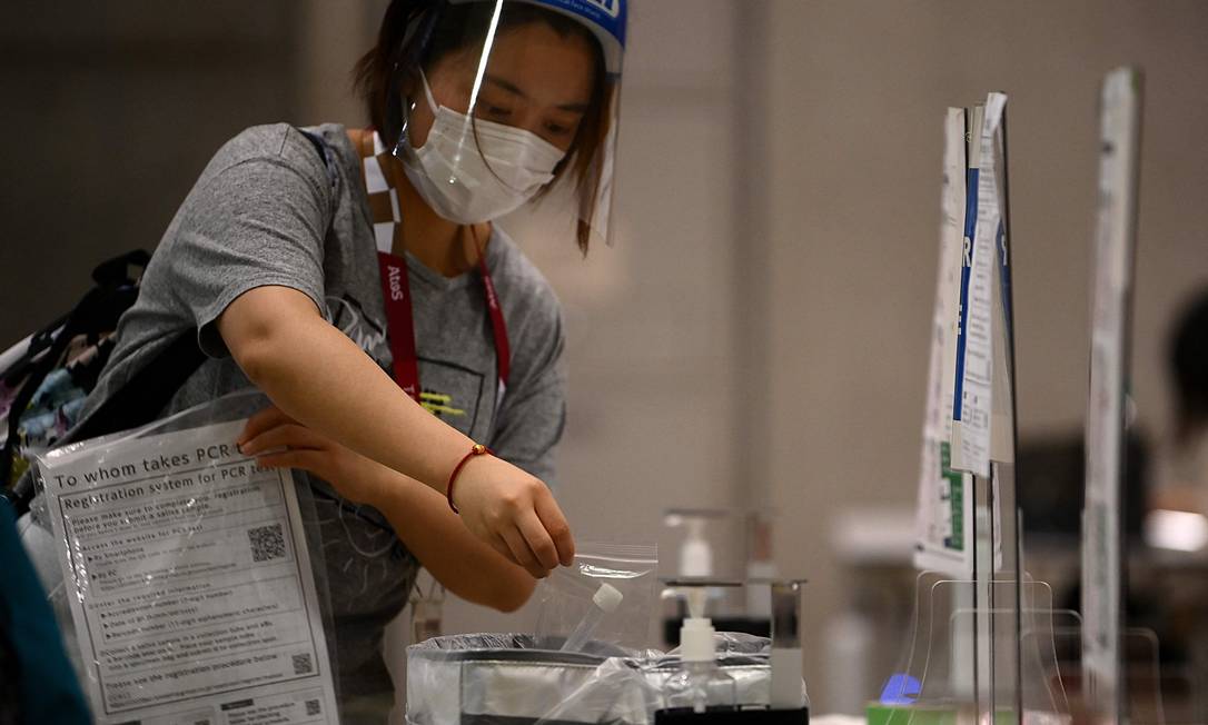 Jornalista deposita amostra de saliva para a realização de teste PCR para Covid-19 em Tóquio: apesar de protocolo, casos positivos vêm aparecendo em atletas Foto: FRANCK FIFE / AFP