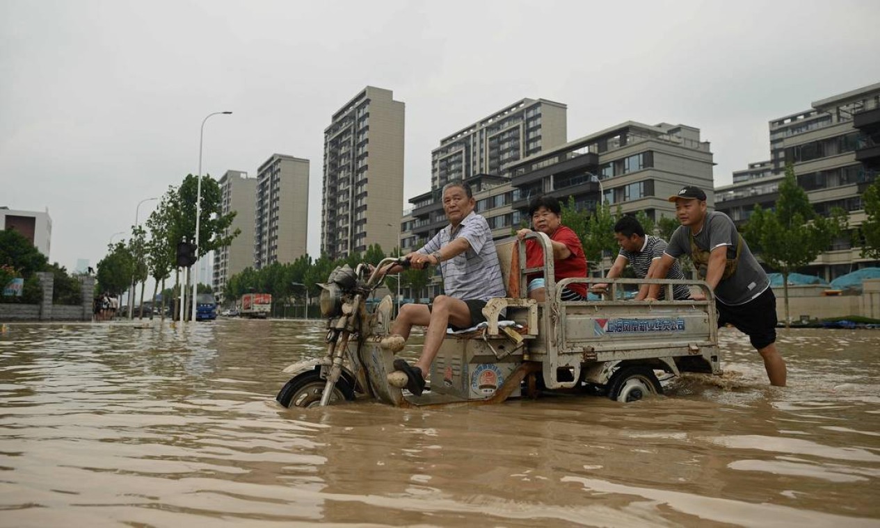 Pessoas caminham por uma rua inundada após uma forte chuva Foto: NOEL CELIS / AFP