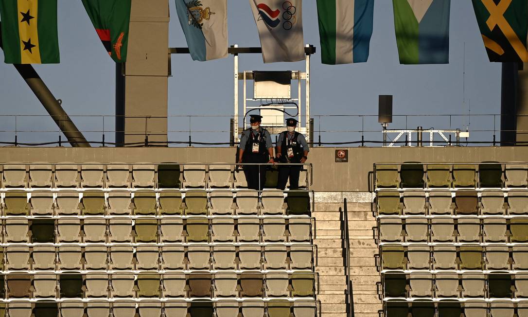 Policiais verificam a tribuna vazia antes da cerimônia de abertura dos Jogos Olímpicos de Tóquio 2020, no Estádio Olímpico, em Tóquio Foto: JEWEL SAMAD / AFP