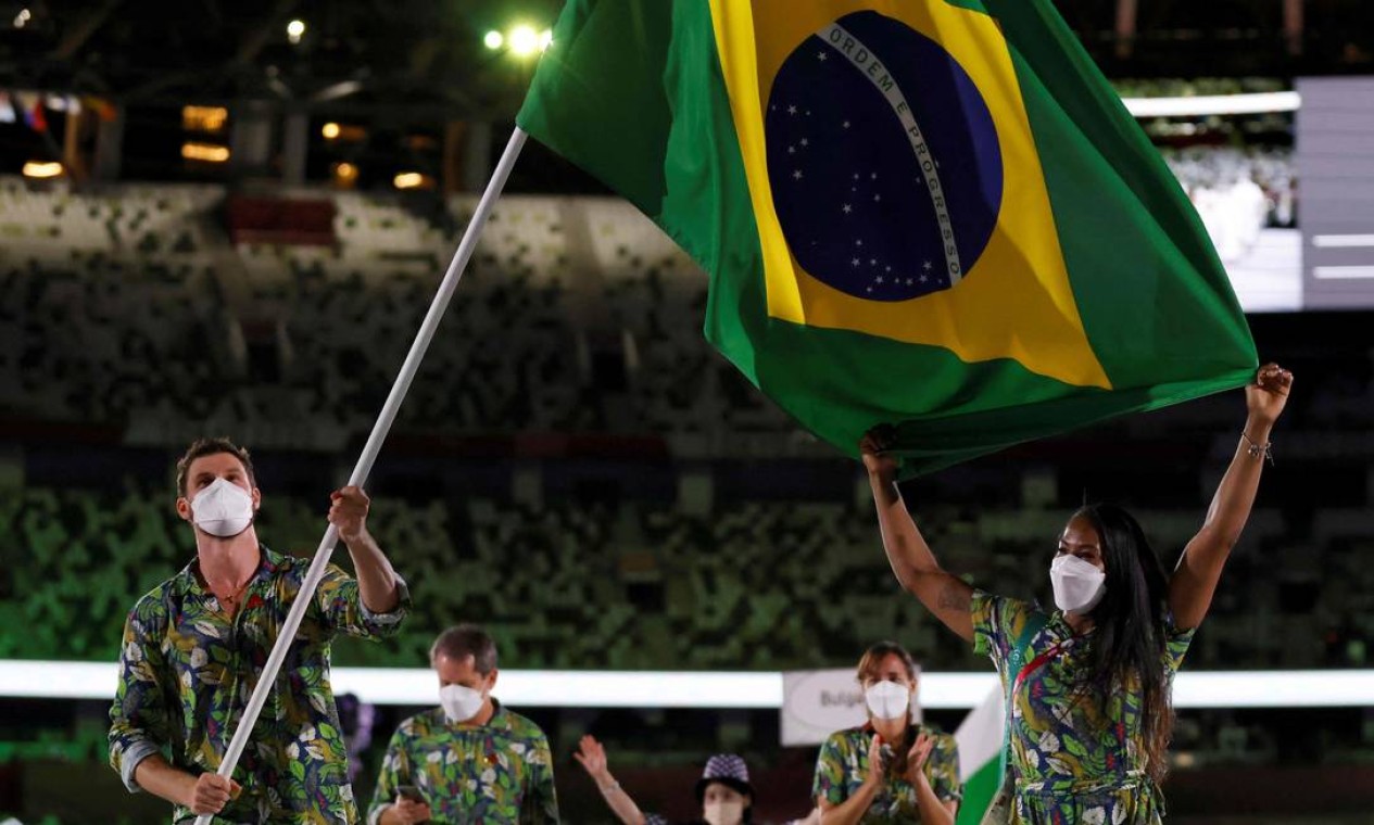 O jogador de vôlei Bruninho e a judoca Ketleyn Quadros levando a bandeira do Brasil em Tóquio Foto: ODD ANDERSEN / AFP