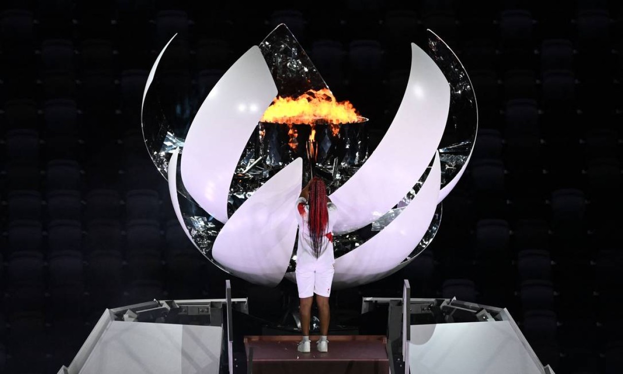 A tenista japonesa Naomi Osaka acende a pira olímpica, que se abre como uma flor a partir da esfera posicionada em cima da reprodução do Monte Fuji no palco da cerimônia de abertura Foto: JEWEL SAMAD / AFP
