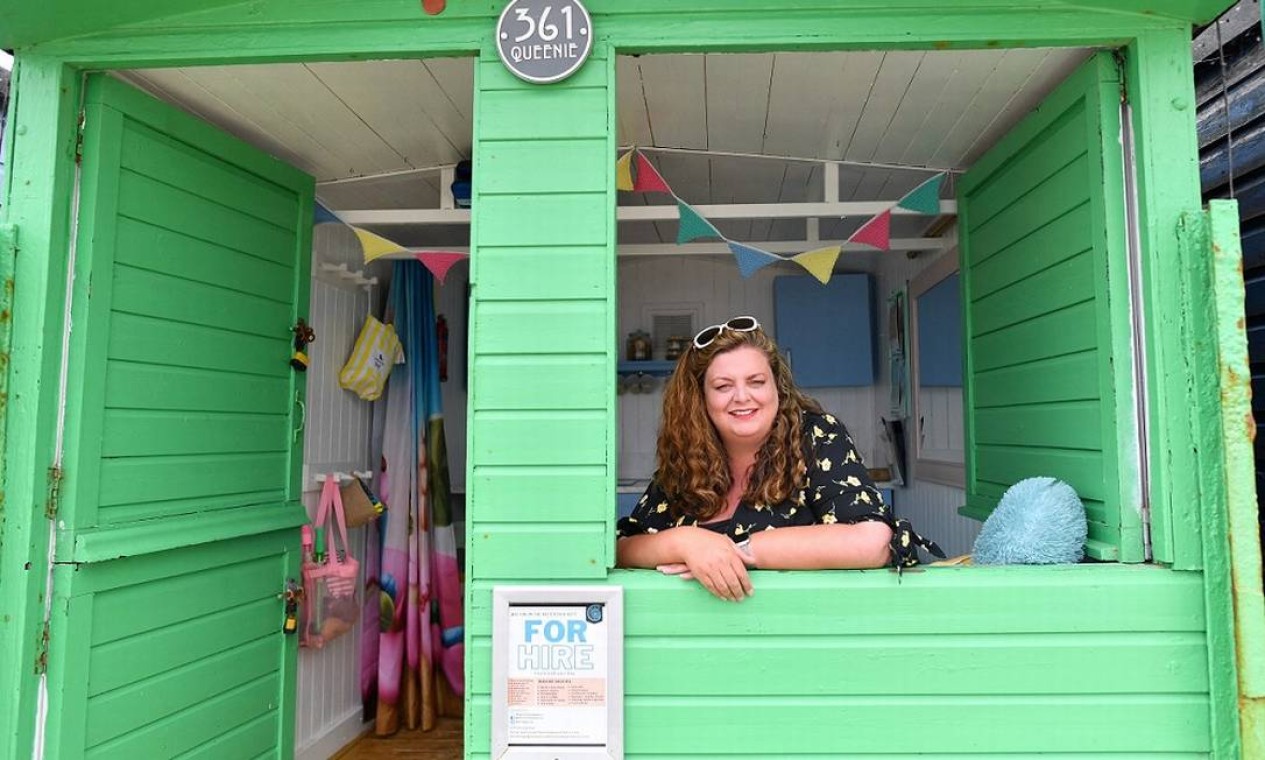 Dona de uma empresa de aluguel de cabanas de praia em Walton-on-the-Naze, Sarah Stimson posa dentro da casinha que usa com a sa família, batizada em homenagem à sua avó Foto: JUSTIN TALLIS / AFP