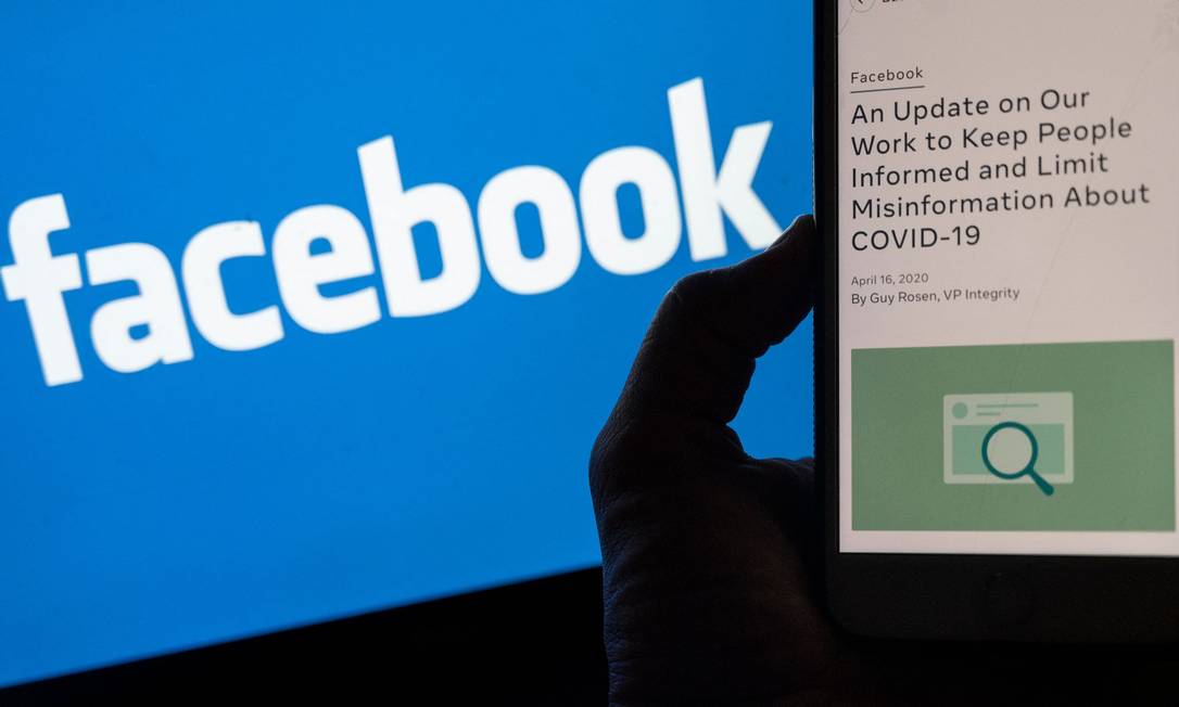 Celular aberto em página do Facebook dedicada a conter desinformações sobre a Covid-19 na rede social Foto: ANDREW CABALLERO-REYNOLDS / AFP