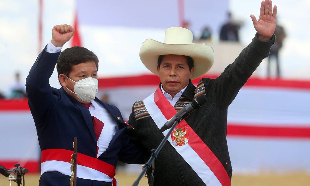 Guido Bellido (à esquerda) e o presidente peruano Pedro Castillo acenam a apoiadores durante a cerimônia simbólica de investidura presidencial em Pampa de la Quinua, em Ayacucho Foto: ERNESTO ARIAS / AFP