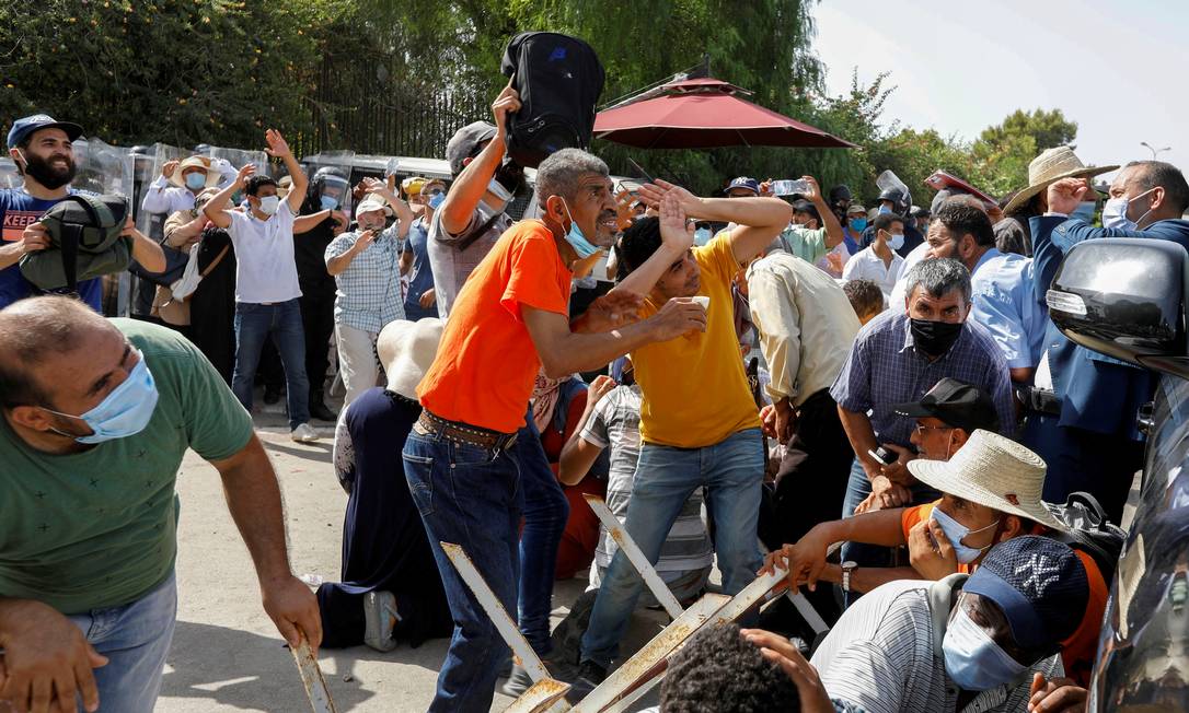 Apoiadores do Ennahda protegem-se das pedras atiradas contra eles por apoiadores do presidente Kais Saied, do lado de fora do Parlamento em Túnis Foto: ZOUBEIR SOUISSI / REUTERS/26-07-2021