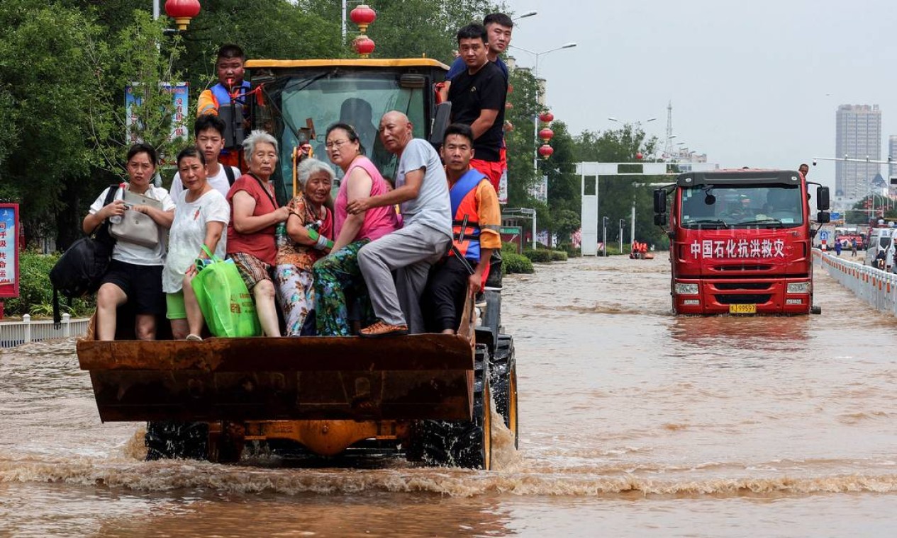 Equipes de resgate evacuam moradores de uma área inundada em Weihui, cidade de Xinxiang, na província chinesa de Henan Foto: STR / AFP