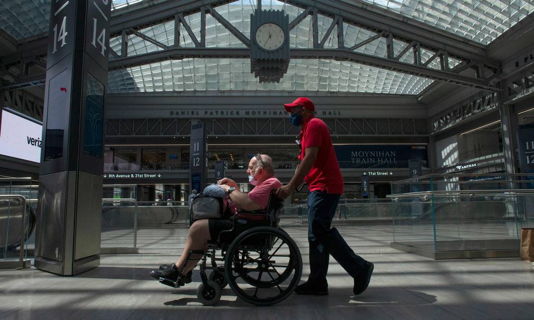 Um homem usando máscara empurra cadeira de rodas em Nova York: proteção facial não é mais obrigatória Foto: KENA BETANCUR / AFP