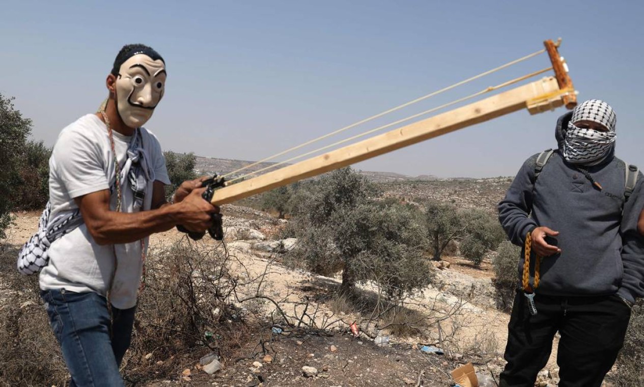 Manifestante palestino usa uma besta improvisada contra forças israelenses durante protesto contra o posto avançado israelense de Eviatar, na vila de Beita, ao norte da Cisjordânia ocupada Foto: JAAFAR ASHTIYEH / AFP