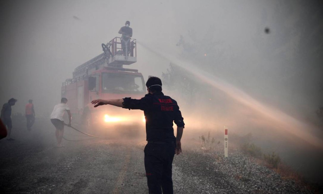 Bombeiros e voluntários lutam para extinguir um incêndio florestal em Akcakoca, na região de férias de Mugla, na Turquia Foto: SERDAR GURBUZ / AFP
