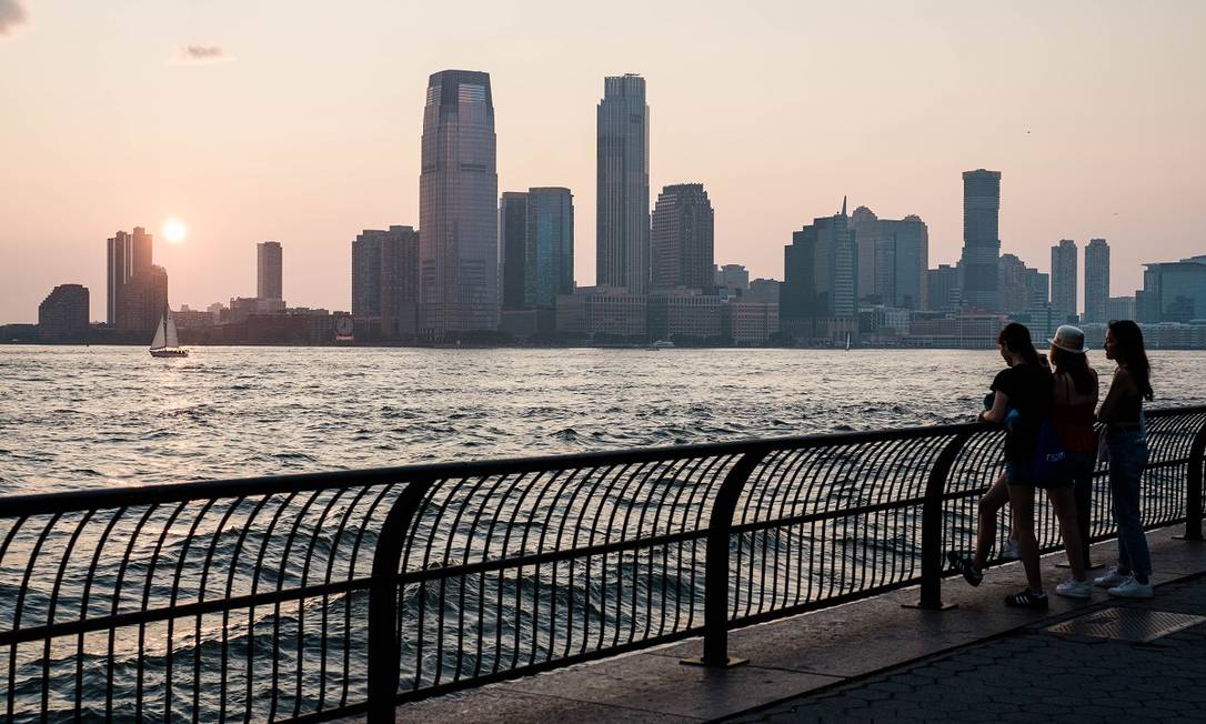 Pessoas apreciam o pôr do sol no Battery Park, no extremo sul da Ilha de Manhattan, em Nova York Foto: Gabriela Bhaskar / The New York Times
