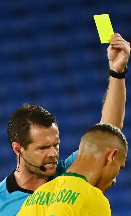 O árbitro australiano Chris Beath mostra o cartão amarelo ao brasileiro Richarlison Foto: LOIC VENANCE / AFP