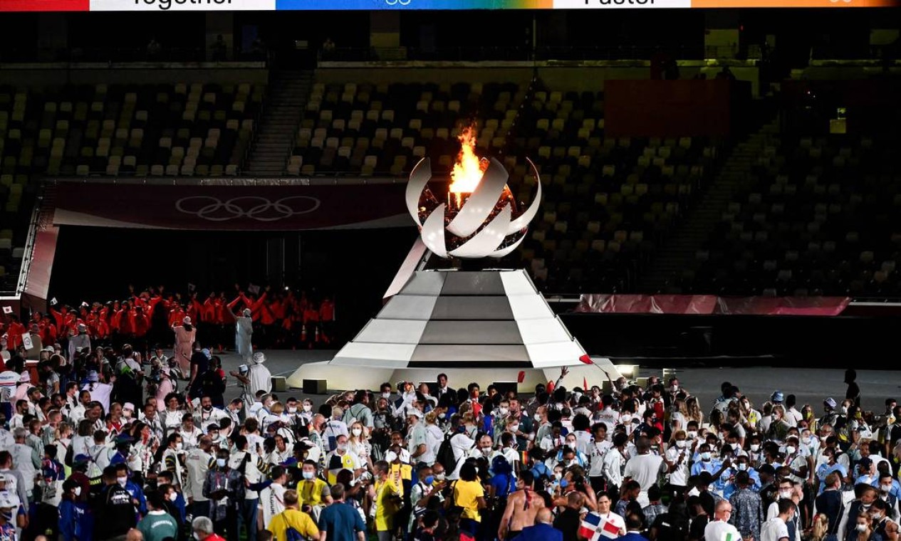 Atletas celebram a festa do esporte perto da chama olímpica durante a cerimônia de encerramento dos Jogos de Tóquio Foto: JEWEL SAMAD / AFP