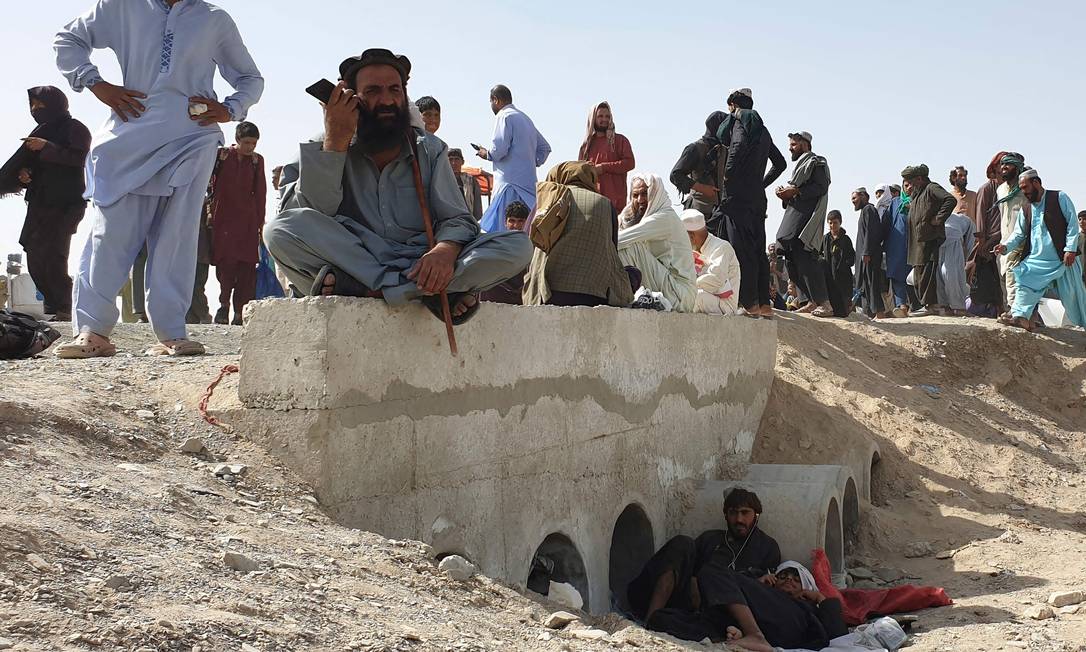 Afegãos aguardam a reabertura do posto de fronteira de Chaman, na fronteira com o Paquistão, fechado depois que o Talibã assumiu o controle da região Foto: ASGHAR ACHAKZAI / AFP