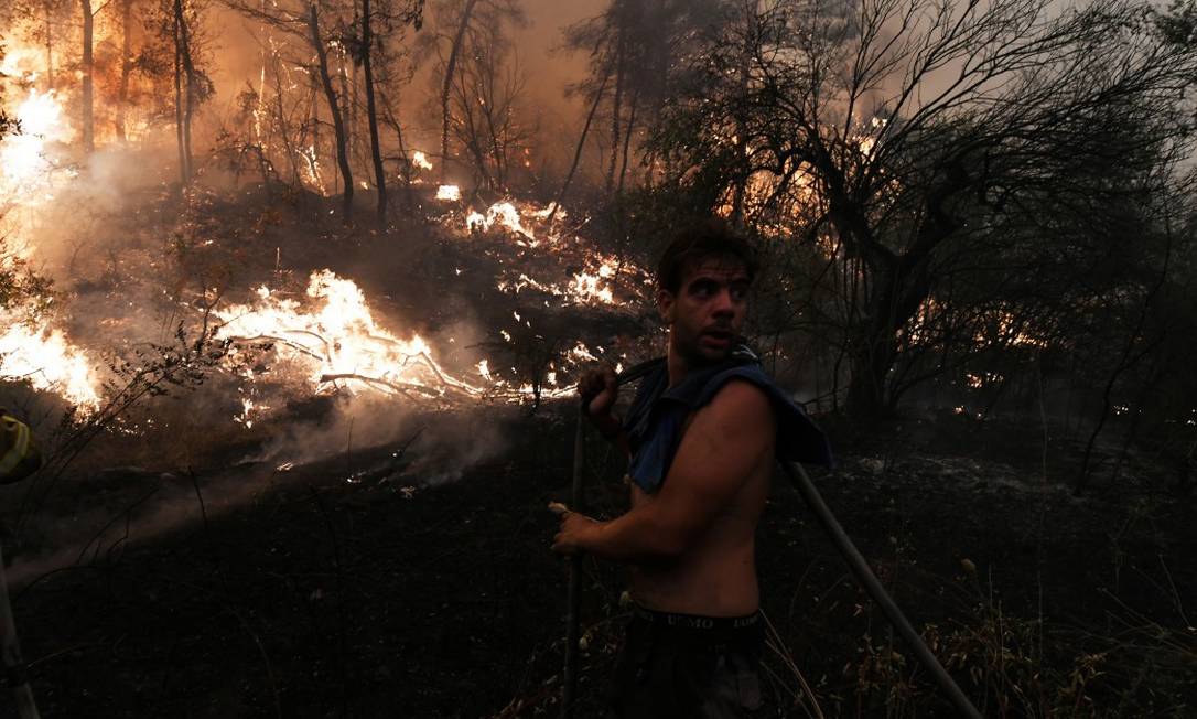 With a hose, a resident tries to contain the flames during a fire on Euboea Island, Greece. Photo: ALEXANDROS AVRAMIDIS / REUTERS