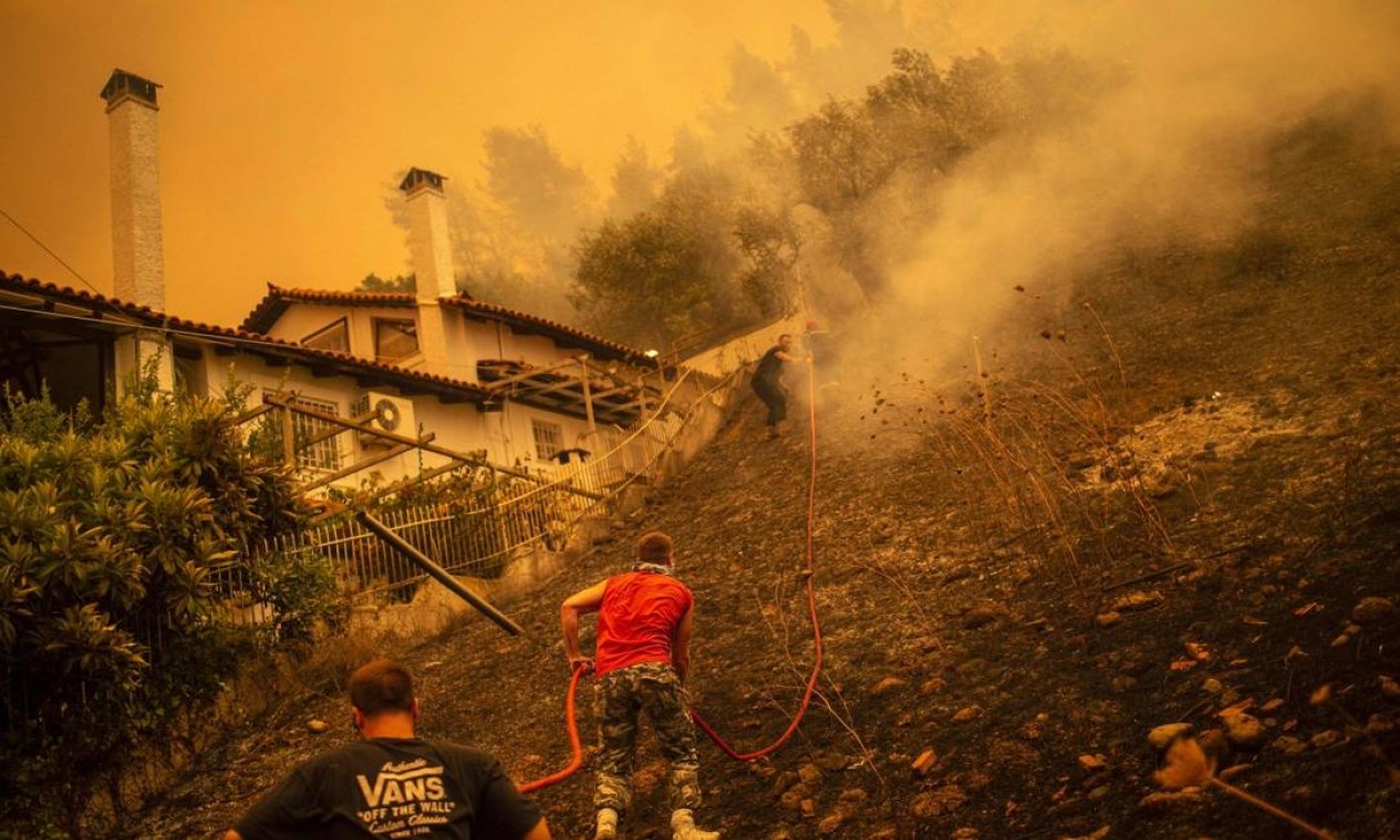 Moradores tentam ajudar bombeiros e militares em incêndio na ilha de Eubeia Foto: ANGELOS TZORTZINIS / AFP