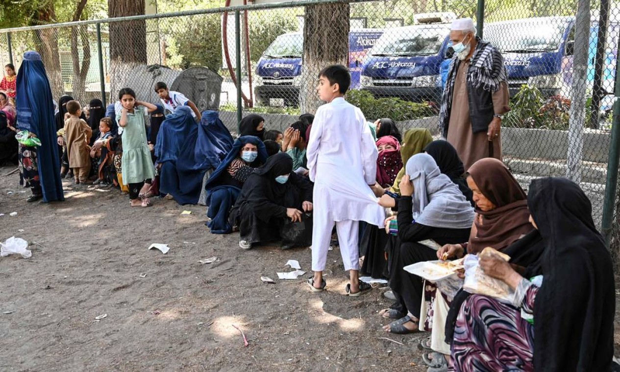 Famílias afegãs almoçam no Parque Shahr-e-Naw, em Cabul. Na manhã de segunda-feira, diversos afegãos chegaram ao espaço, em Cabul, que se tornou um abrigo improvisado Foto: WAKIL KOHSAR / AFP