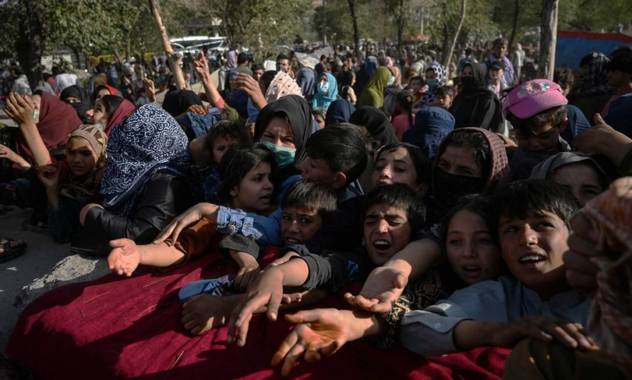 Afegãos que deixaram suas casas tentam pegar comida em um acampamento improvisado na capital, Cabul Foto: WAKIL KOHSAR / AFP