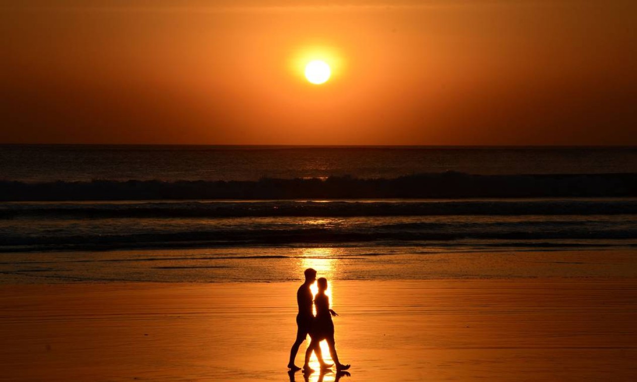 As pessoas caminham durante o pôr do sol na praia de Kuta, na ilha de Bali, na Indonésia Foto: SONNY TUMBELAKA / AFP