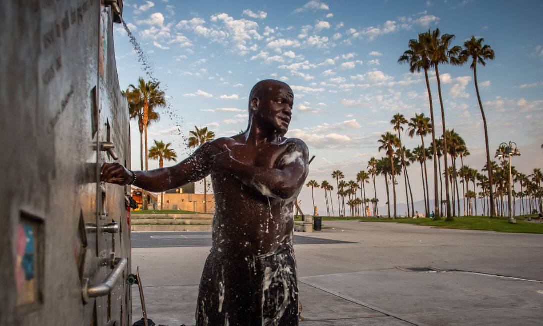 Jamal, who has lived on the streets for 18 years, bathes in the rain on a public beach in Venice, California Photo: APU GOMES / AFP