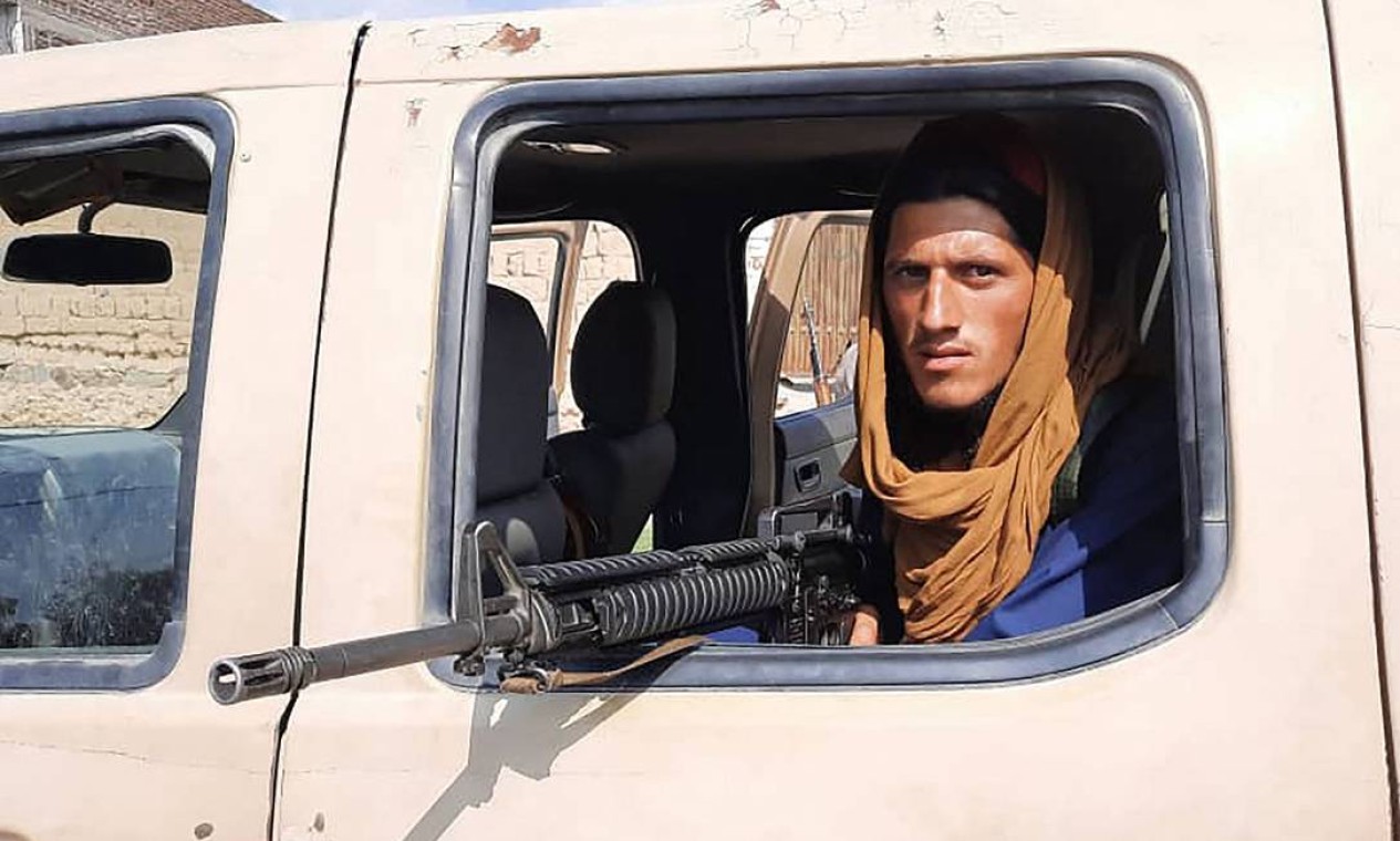 Soldado do Talibã põe arma para fora de um veículo do Exército afegão em estrada na província de Laghman Foto: - / AFP