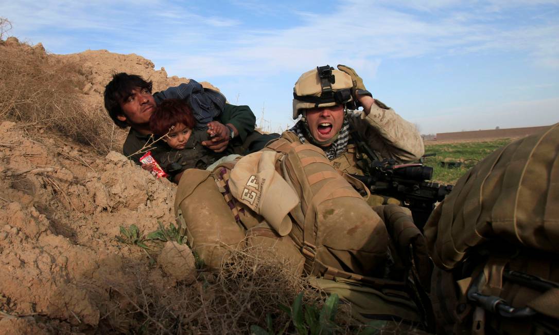 Militar da Marinha dos EUA tenta proteger afegão com o filho durante confronto com Talibã, no distrito de Nad Ali, província de Helmand, Afeganistão Foto: GORAN TOMASEVIC / REUTERS - 13/02/2010
