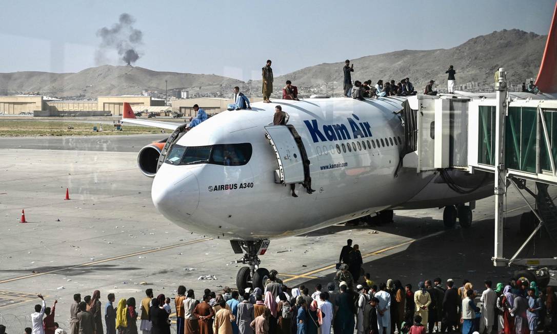Pessoas sobem em avião comercial estacionado no aeroporto de Cabul em uma tentativa de fugir do Afeganistão Foto: WAKIL KOHSAR / AFP