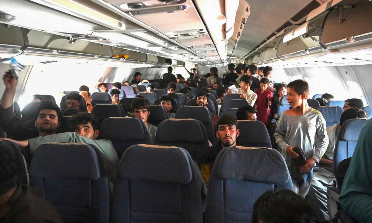 Passageiros afegãos sentam-se dentro de um avião enquanto esperam para deixar o aeroporto de Cabul Foto: WAKIL KOHSAR / AFP