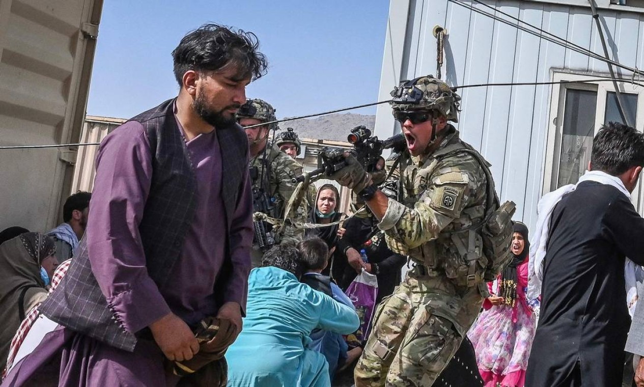 AGOSTO - Soldado dos EUA aponta arma para passageiro afegão no aeroporto de Cabul, palco de cenas de desespero, depois que os EUA retiraram suas tropas do Afeganistão, depois de 20 anos de ocupação militar no país. Foto: WAKIL KOHSAR / AFP