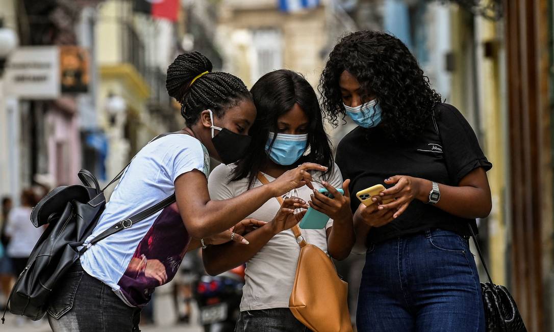 Garotas usam seus celulares na rua em Havana, Cuba Foto: YAMIL LAGE / AFP/14-07-2021