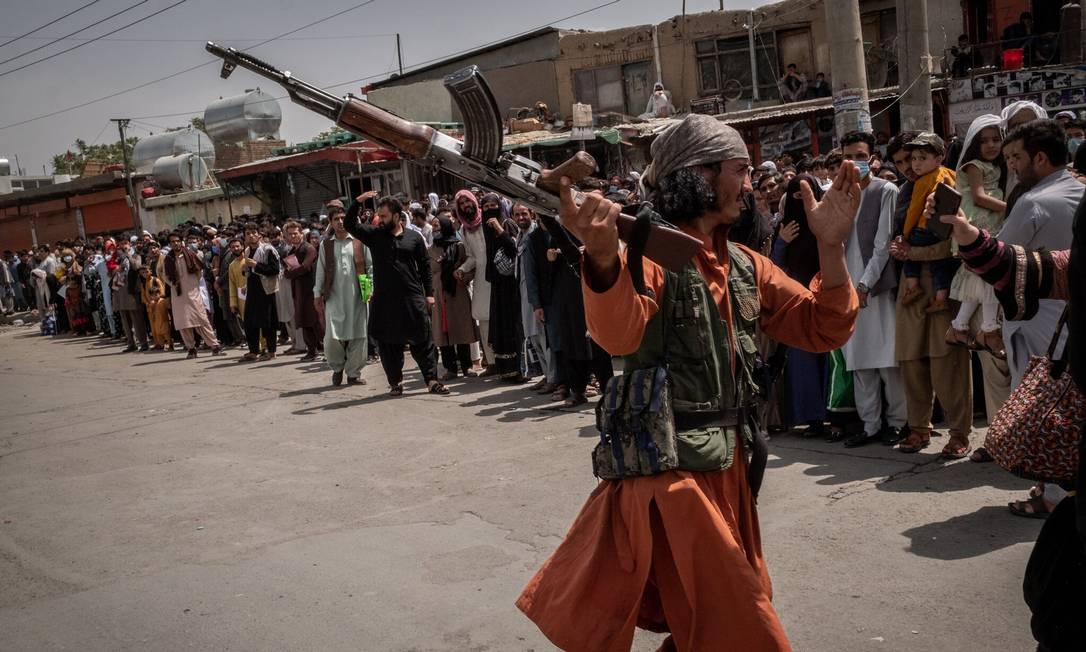 Soldado do Talibã tenta agredir mulher que esperava para entrar no aeroporto internacional de Cabul Foto: Jim Huylebroek / NYT