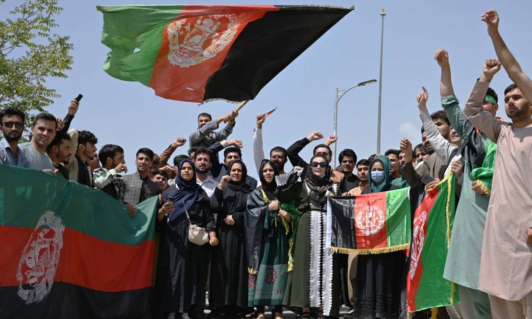 Afegãos carregam a flâmula tricolor do país, símbolo que o Talibã vem gradualmente substituindo por sua bandeira em preto e branco Foto: WAKIL KOHSAR / AFP