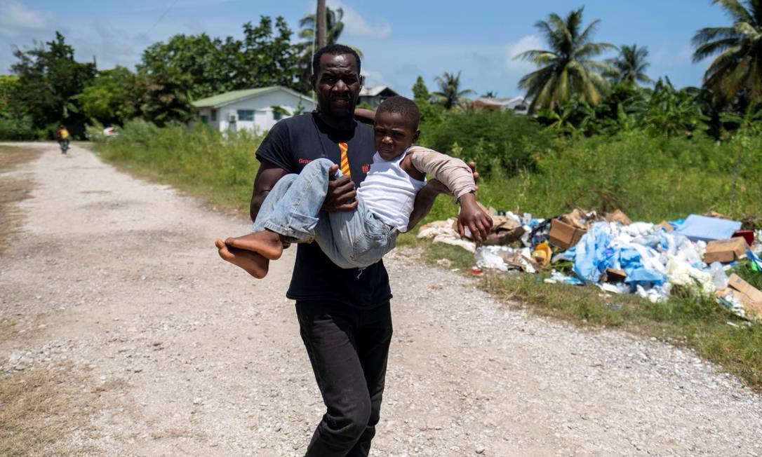 Homem carrega criança machucada para hospital em Les Cayes, Haiti Foto: RICARDO ARDUENGO / REUTERS