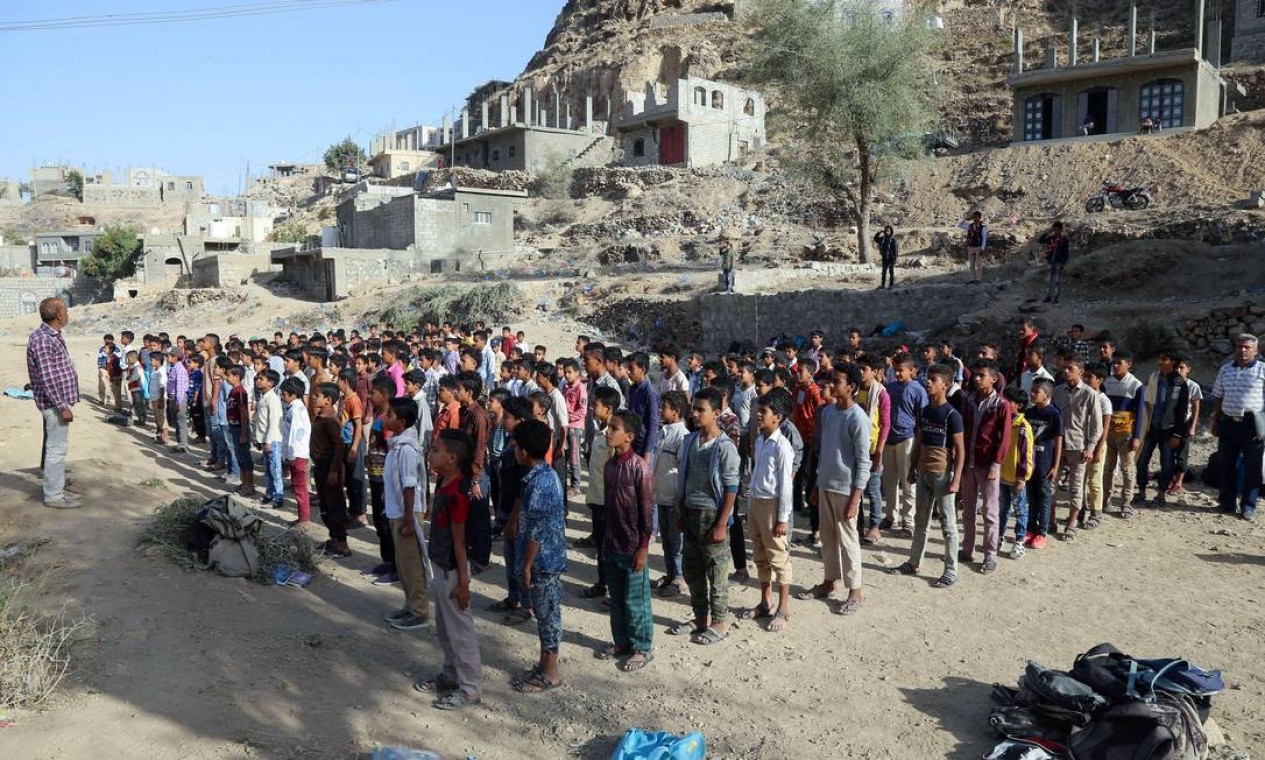 Alunos iemenitas participam da chamada matinal antes do início das aulas em edifícios residenciais e comerciais inacabados convertidos em uma escola e salas de aula na Escola Al-Thalaya na terceira cidade do Iêmen de Taez Foto: AHMAD AL-BASHA / AFP