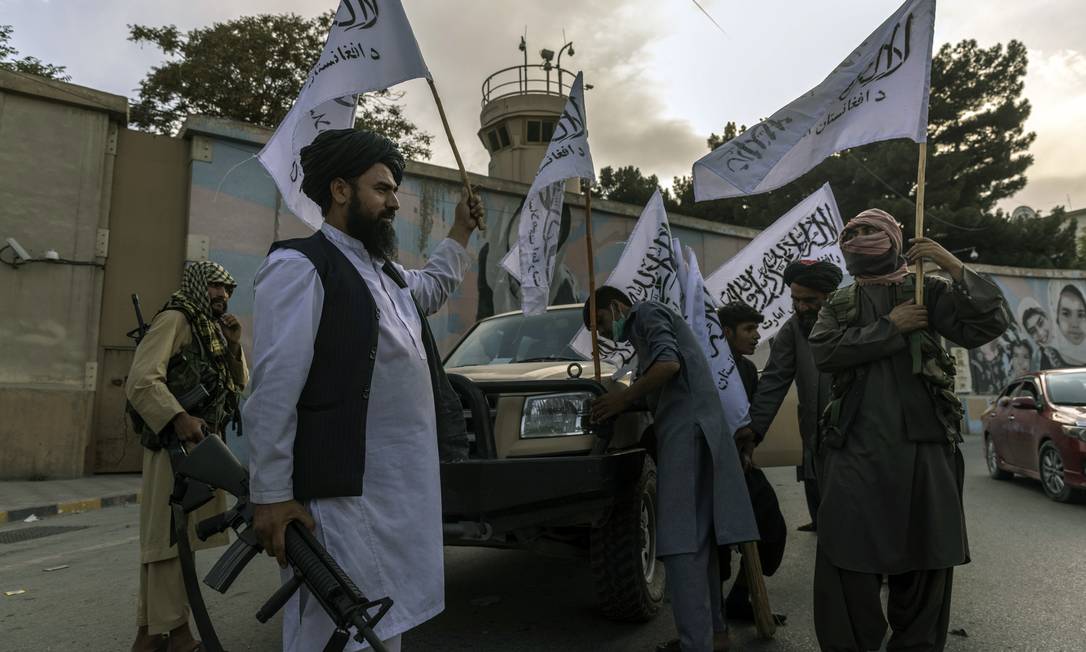 Soldados do Talibã carregam bandeiras do grupo nos arredores da Embaixada americana em Cabul Foto: VICTOR J. BLUE / NYT/22-8-21