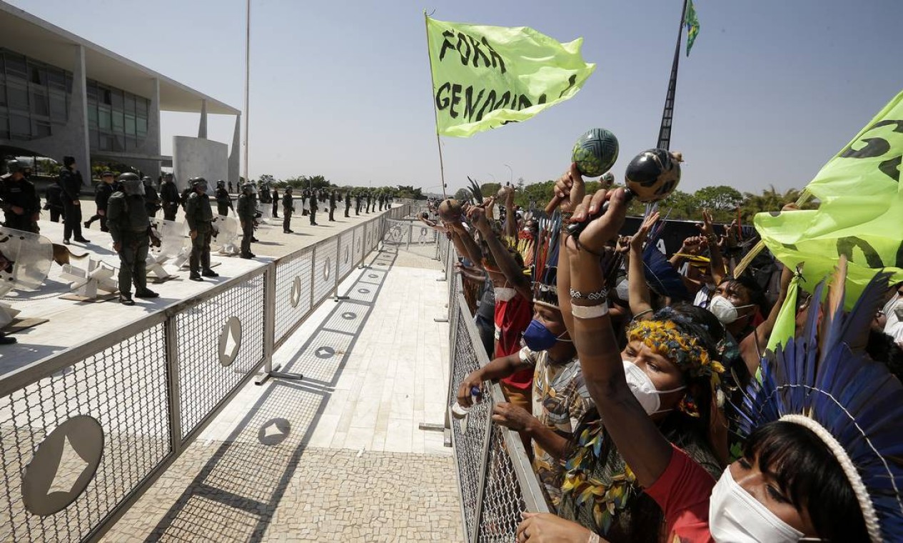 Indígenas protestam diante de uma barreira instalada em frente ao Palácio do Planalto monitorados por policiais Foto: Cristiano Mariz / Agência O Globo - 27/08/2021