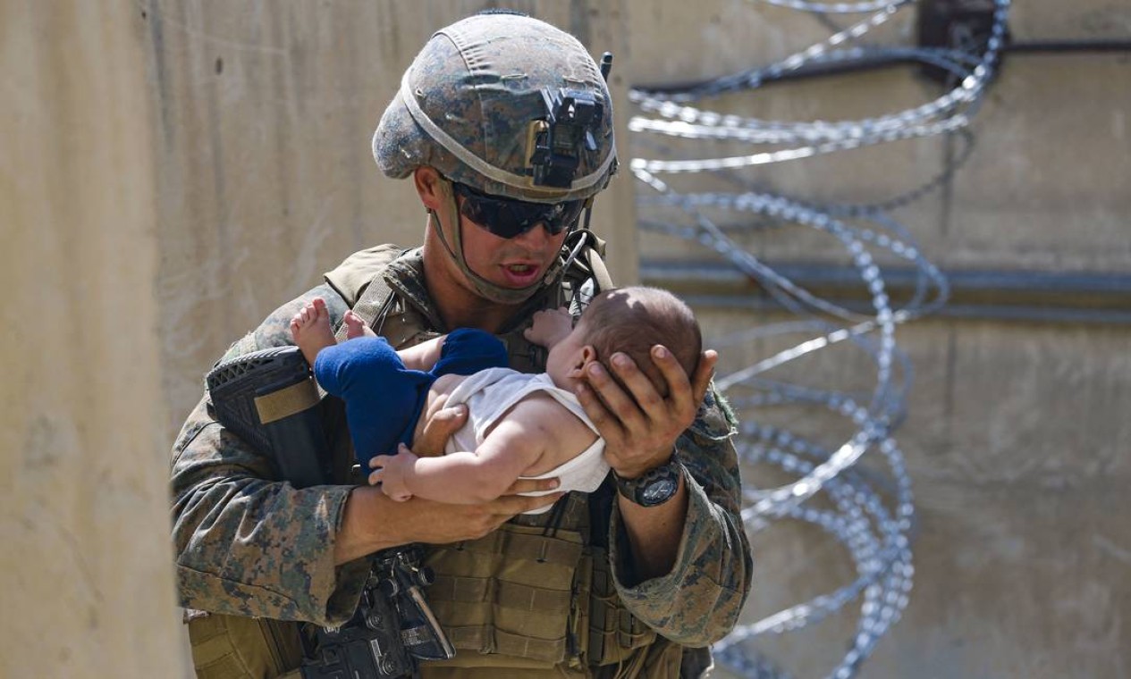 Fuzileiro dos EUA conforta uma criança enquanto espera pela mãe durante uma evacuação no Aeroporto Internacional de Cabul, Afeganistão Foto: NICHOLAS GUEVARA / AFP