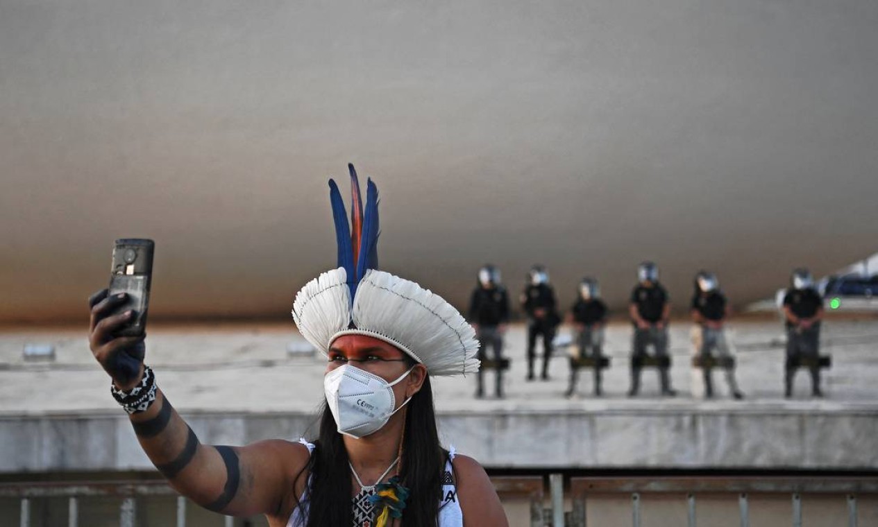 Mulher indígena tira selfie em frente à tropa de choque durante manifestação em frente ao prédio do Supremo Tribunal Federal, em Brasília Foto: CARL DE SOUZA / AFP
