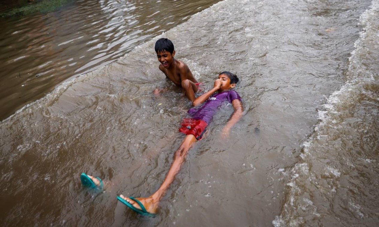 Crianças brincam em uma rua inundada após fortes chuvas em Nova Delhi, Índia Foto: ADNAN ABIDI / REUTERS