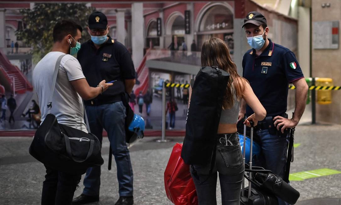 Policiais verificam certificado sanitário em estação de trem de Turim, na Itália Foto: MARCO BERTORELLO / AFP
