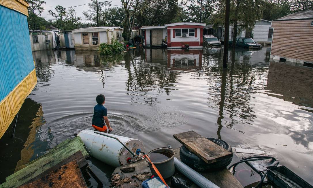 Criança mira casa de seu avô após inundação provocada pelo furacão Ida em Barataria, Louisiana Foto: Brandon Bell / AFP/31-08-2021