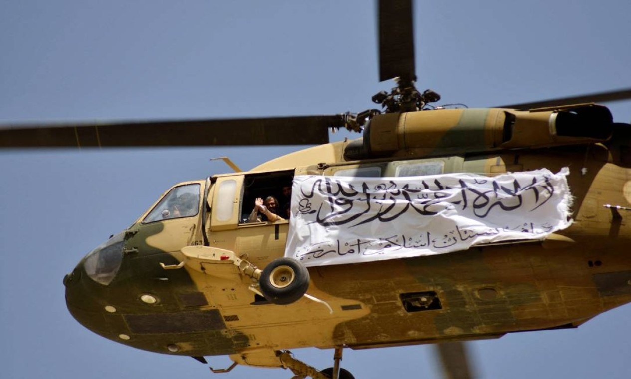Helicóptero exibindo uma bandeira do Talibã sobrevoa apoiadores para comemorar a retirada dos EUA de todas as suas tropas do Afeganistão, em Kandahar Foto: JAVED TANVEER / AFP