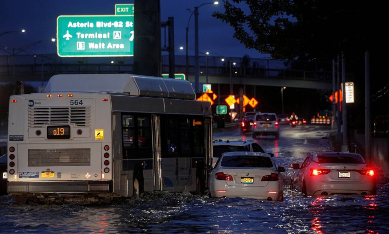 Ônibus passa por carros abandonados em uma rodovia inundada, no bairro de Queens, em Nova York Foto: BRENDAN MCDERMID / REUTERS