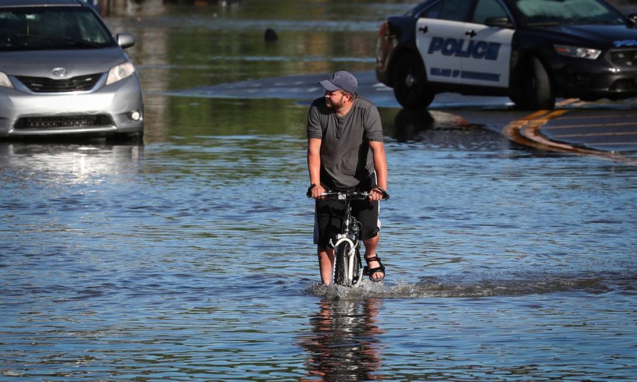 Homem anda de bicicleta pelas águas da enchente enquanto moradores deixam suas casas depois que os restos da tempestade tropical Ida provocou chuva torrencial, enchentes e tornados para partes do nordeste em Mamaroneck, Nova York Foto: MIKE SEGAR / REUTERS