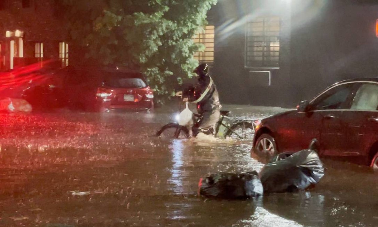 Homem empurra uma bicicleta em uma rua inundada de Nova York Foto: JOHNNY MILLER / UNEQUAL SCENES / via REUTERS