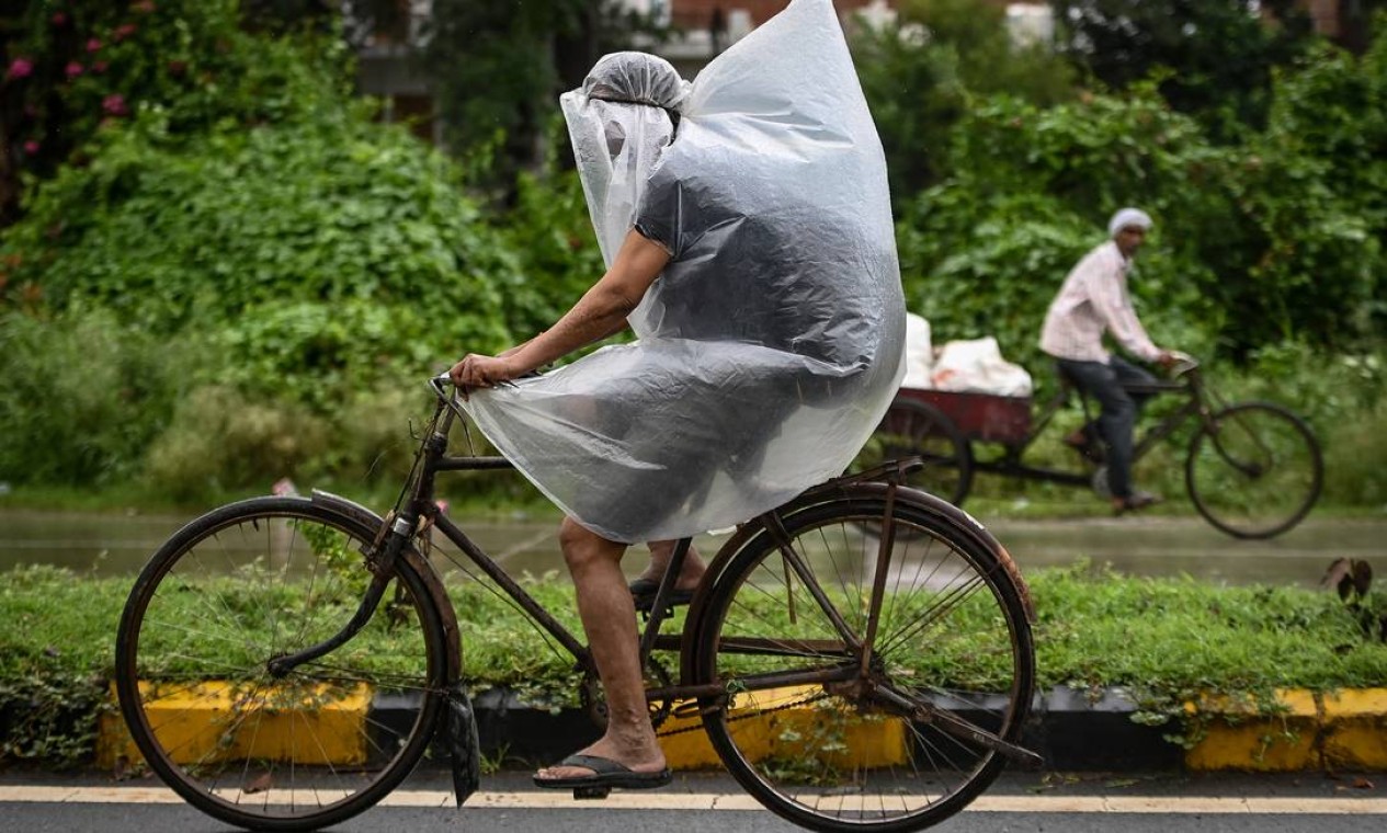 Ciclista coberto por plástico durante uma chuva torrencial em Faridabad, na Índia Foto: MONEY SHARMA / AFP