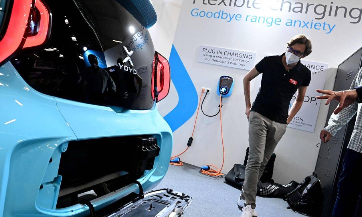 Visitante observa o sistema de troca e carregamento de bateria para um carro elétrico impresso em 3D XEV Yoyo Foto: TOBIAS SCHWARZ / AFP